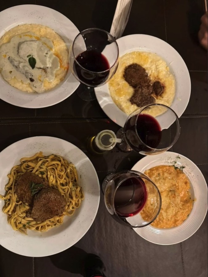 Mesa com risotos e massas servidos com vinho