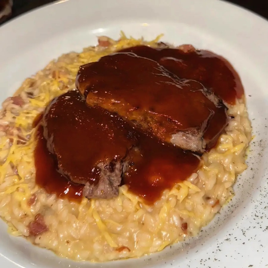 Prato com filé mignon sobre risoto e molho